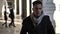 Young man walking and wearing scarf under colonnade