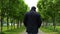 A young man walks along the alley in the park.