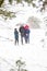 Young man in warm hat and child girl and boy on rural winter snowy background holding umbrella. Happy family, cold