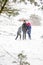 Young man in warm hat and children girl and boy on rural winter snowy background holding umbrella. Happy family, cold