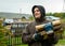 A young man in a warm jacket and a hood carries firewood. He has rubberized gloves on his hands