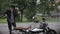 Young man washing his scrambler motorbike with water hose on the street