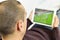 Young man watching a soccer match in his tablet
