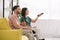 Young man watching tv together with disabled girlfriend while sitting on sofa at home