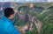 Young man watching waterfall streams falling from mountain top covered with green forests at day