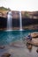 Young man with waterfall streams falling from mountain top at morning long exposure shot