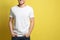 Young man wearing blank t-shirt on yellow background, closeup. Mockup for