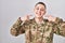 Young man wearing camouflage army uniform smiling cheerful showing and pointing with fingers teeth and mouth