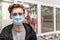 Young man wearing disposable medical mask shopping in supermarket during coronavirus