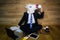 Young man wearing funny mask sits on the floor against a wall and drinks coffee