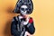 Young man wearing mexican day of the dead costume over yellow serious face thinking about question with hand on chin, thoughtful