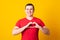 Young man wearing red t-shirt smiling in love doing heart symbol shape with hands. Romantic concept