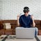 Young man wearing two sunglasses and holding two more glasses facing to computer screen..Asian man sell various styles of