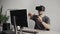 Young man wearing virtual reality goggles headset and sitting in the office against computer and trying to touch objects