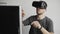 Young man wearing virtual reality goggles headset and sitting in the office against computer and trying to touch objects