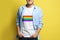 Young man wearing white t-shirt with image of LGBT pride flag on yellow background