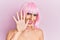 Young man wearing woman make up wearing pink wig showing and pointing up with fingers number five while smiling confident and