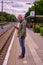 Young man wears an FFP1 a face mask while waiting on a trainstation. He is protecting himself from coronavirus.