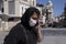 Young man wears protective mask and walks around the street and makes phone call