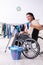 Young man in wheel-chair doing ironing at home