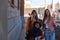 Young man in a wheelchair next to two happy young girls walking down the street