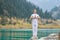 A young man in white practices yoga in the mountains. Pose Samasthiti namaskar