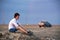 A young man in a white shirt sits on a rocky plateau