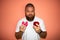 Young man with white t-shirt and big beard making difficult choice between red apple and pink donut