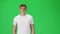 Young man in a white t-shirt going and looking forward against a green background. Slow motion.