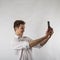 Young man in white using smartphone. Man taking selfie over bright background