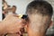 Young man who have gray hair being haircut with electric clipper machine by professional barber in barbershop