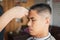 Young man who have gray hair being haircut with electric clipper machine by professional barber in barbershop