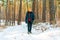 Young man in winter walks in winter snowy pine forest