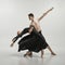 Young man and woman, ballet dancers performing on stage  over grey studio background. Lightness and freedom