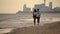 Young man and woman barefooted walking hand in hand on the sand beach slow motion girl and her boyfriend spending