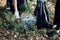 Young man and woman cleaning up a forest. Volunteers picking plastic waste to bags