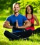 Young man and woman doing yoga in the sunny summer