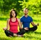 Young man and woman doing yoga in the sunny summer