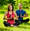 Young man and woman doing yoga in the sunny summer park