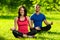 Young man and woman doing yoga in the sunny summer park