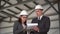 Young man and woman in helmets with documents at a construction site. Businessmen in suits conclude an agreement. A