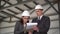 Young man and woman in helmets with documents at a construction site. Businessmen in suits conclude an agreement. A