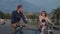 Young man and woman are meeting and riding bikes in park in daytime