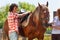 Young man and woman saddling chestnut brown horse