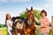 Young man and woman saddling their bay horse