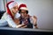 Young man and woman in santa hat at Xmas party at office take selfie