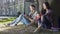 Young man and woman sitting under tree, being shy at first meeting, awkwardness