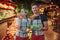 Young man and woman stand at fruit boxes in grocery store. Female model bite orange. Young man hold apples and look on