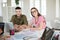 Young man and woman in striped t-shirt and eyeglasses happily looking in camera while working together. Group of cool