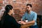 Young man and woman talking holding hands in a coffee shop on the background of a rough brick wall